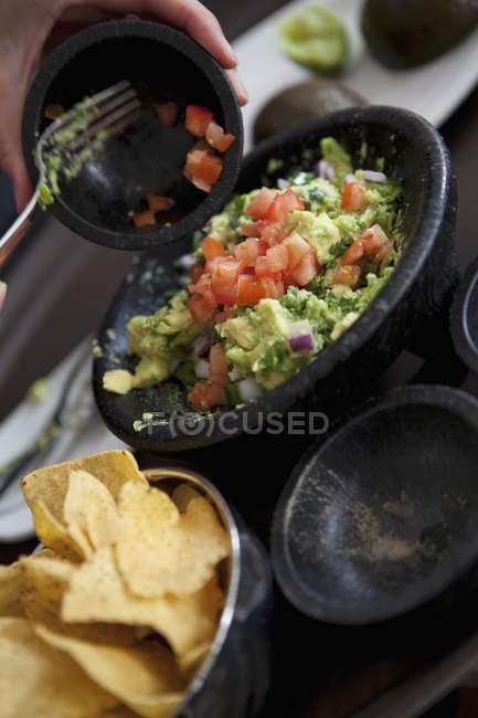 Woman Making Guacamole on Lap with Mortar and Pestle — Stock Photo
