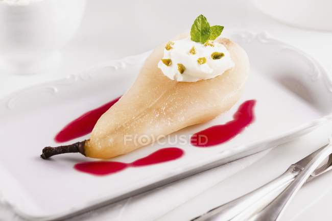 Closeup view of pear poached in amaretto with cranberry sauce — Stock Photo