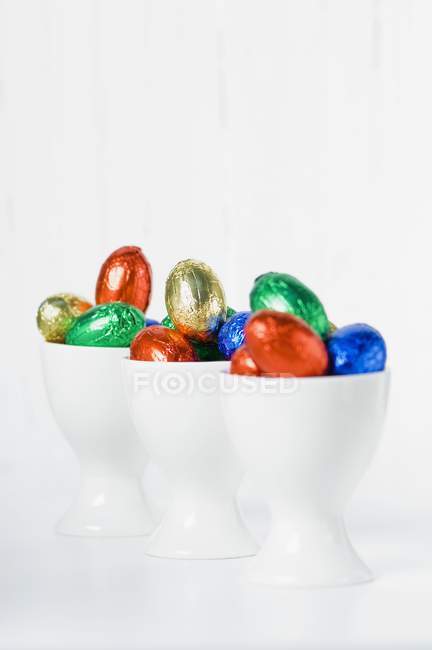 Colourful chocolate eggs in eggcups — Stock Photo