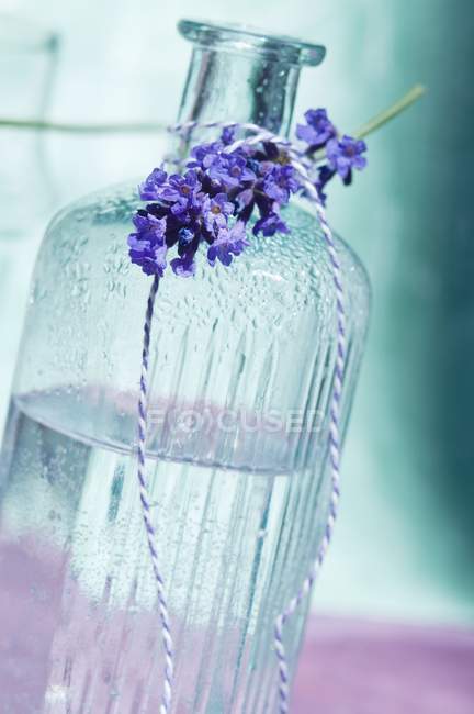 Vista close-up de uma garrafa de água e um raminho amarrado de lavanda — Fotografia de Stock