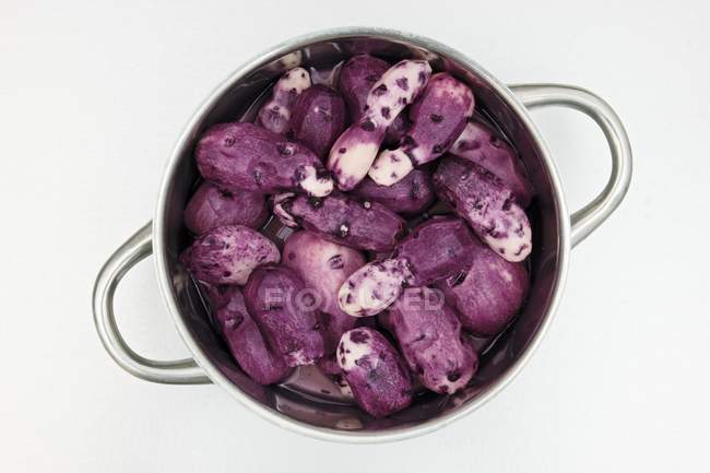 Purple Vitelotte patatas en la sartén - foto de stock