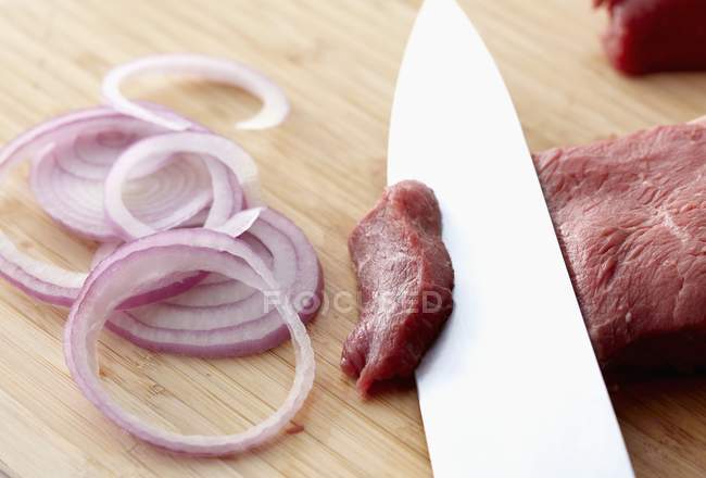 Rohes Rindfleisch und rote Zwiebeln schneiden — Stockfoto