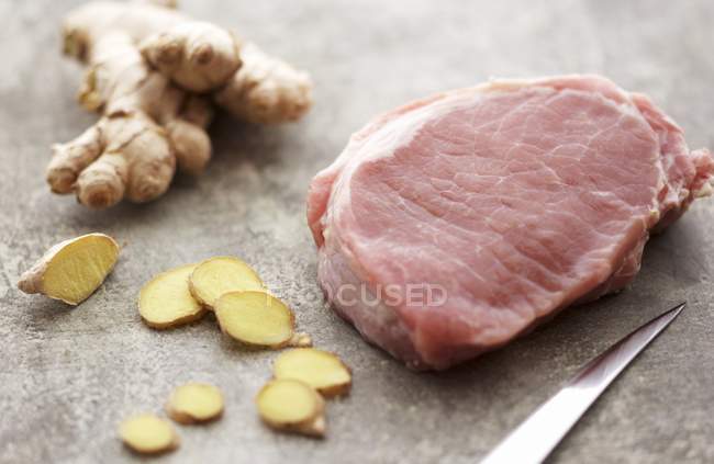 Pieza de cerdo crudo con jengibre en rodajas - foto de stock