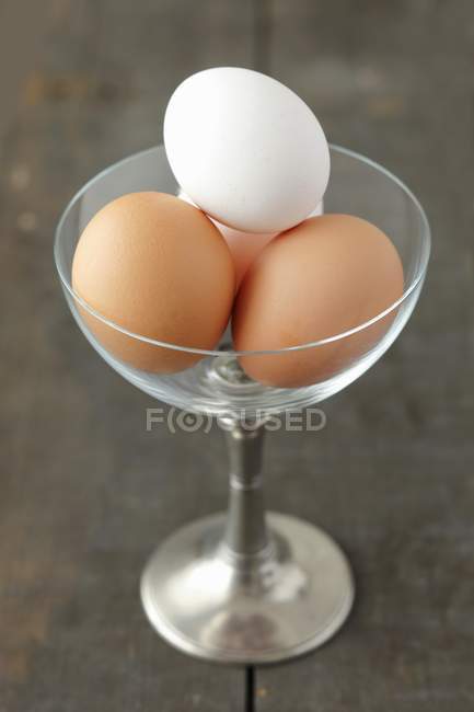Brown and white eggs in glass with stem — Stock Photo