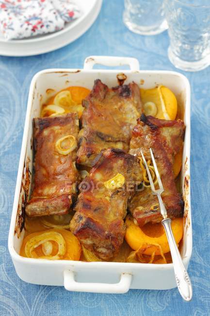 Vista elevada de costillas de cerdo al horno con cebolla, curry en polvo y melocotones - foto de stock