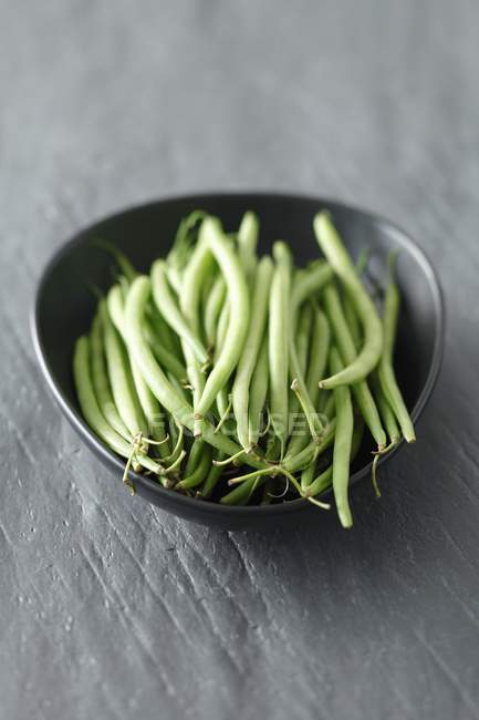 Haricots verts frais dans un bol noir — Photo de stock