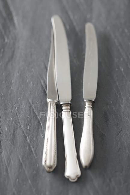 Vista close-up de três facas em uma superfície de ardósia — Fotografia de Stock