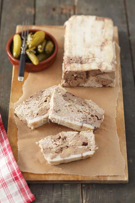 Pt with chicken liver, partly sliced, and a small bowl of pickled gherkins — Stock Photo