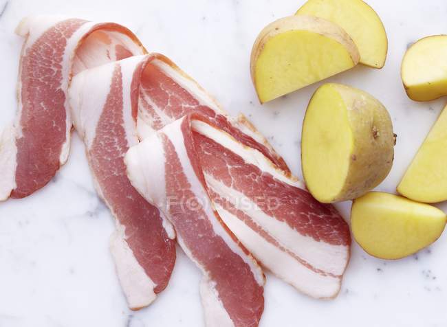 Corte batatas cruas e fatias de bacon — Fotografia de Stock
