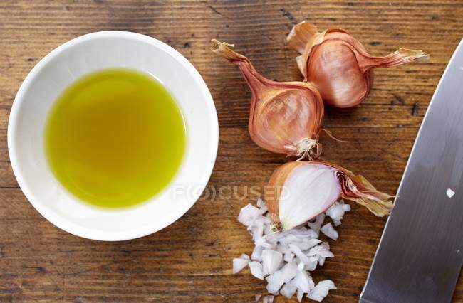 Schalotten fein gehackt und eine Schüssel Olivenöl über die Holzoberfläche — Stockfoto