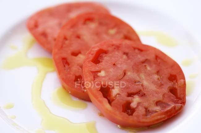 Tomates fatiados em uma placa branca Drizzled com azeite em placa branca — Fotografia de Stock