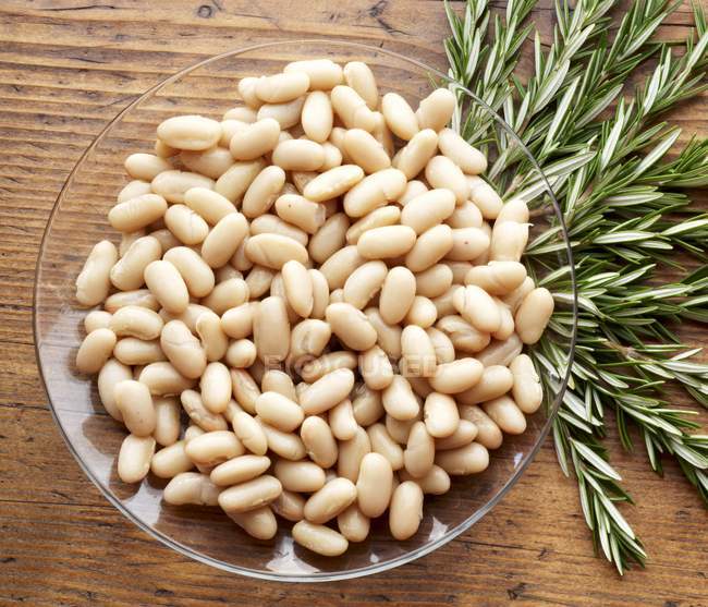 A Bowl of Tuscan Beans with Fresh Rosemary over wooden surface — Stock Photo