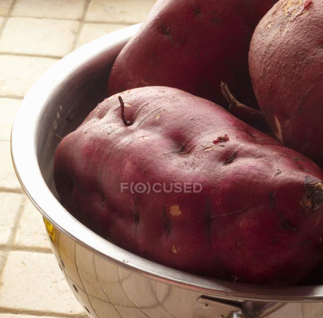 Frische rohe Süßkartoffeln in Metallschale über Holzoberfläche — Stockfoto