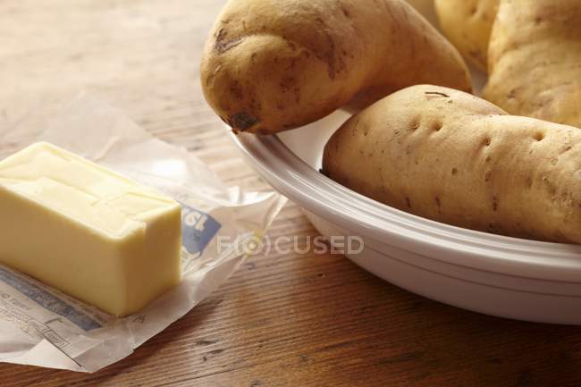 Yams and Butter in plate over wooden surface — Stock Photo
