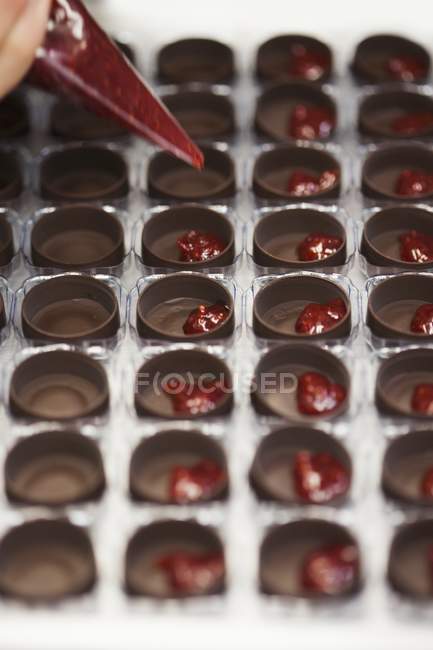 Riempimento di stampi al cioccolato con lampone — Foto stock