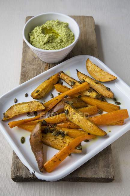 Deep-fried sweet potato wedges with houmous  on white plate over wooden desk — Stock Photo