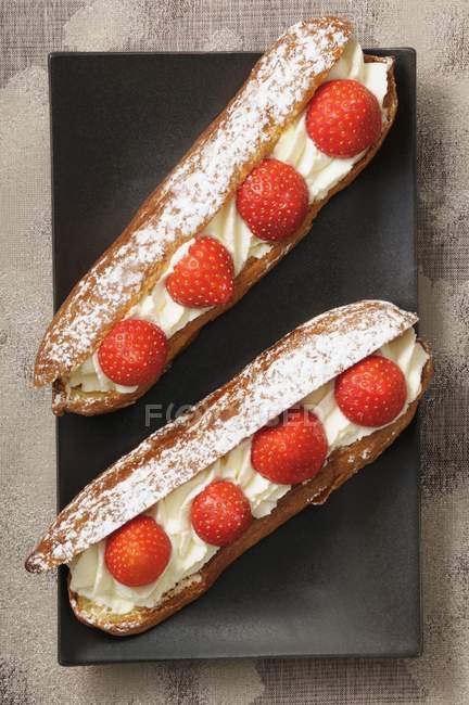 Eclairs with cream and strawberries — Stock Photo