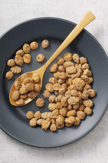 Tiger nuts on black plate — Stock Photo