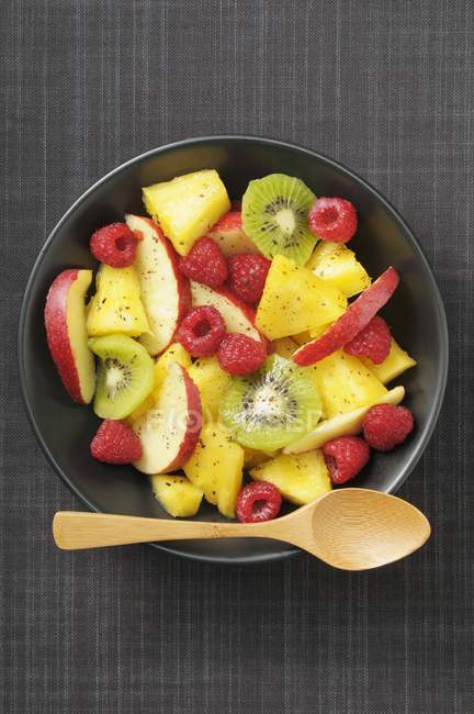Ensalada de frutas con kiwi y frambuesas en un tazón - foto de stock