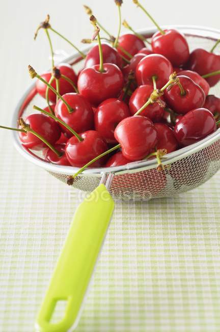 Fresh cherries in sieve — Stock Photo