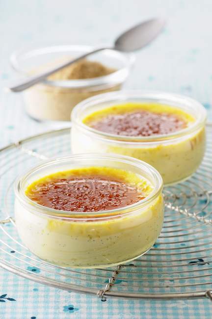 Closeup view of Creme brulee in glass ramekins on wire cooling rack — Stock Photo