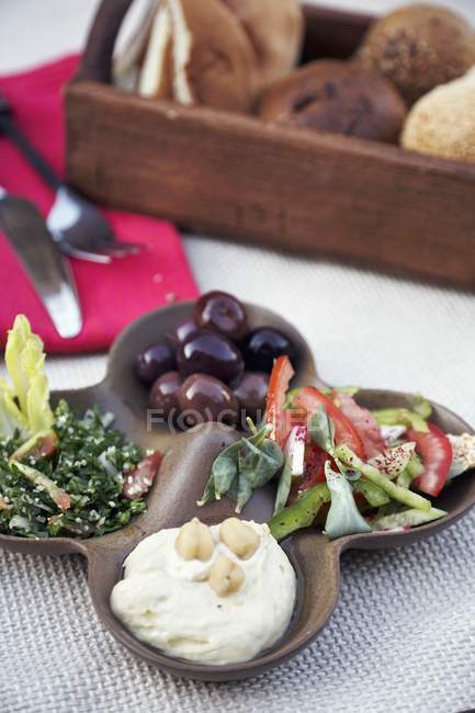 Houmous com azeitonas e salada no prato — Fotografia de Stock