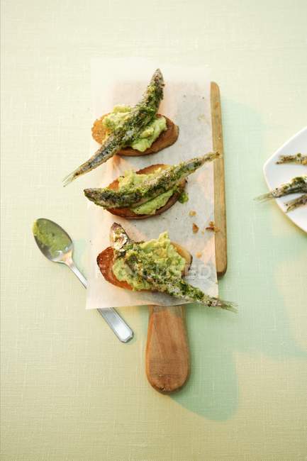 Top view of Crostini with anchovies on paper and wooden board — Stock Photo