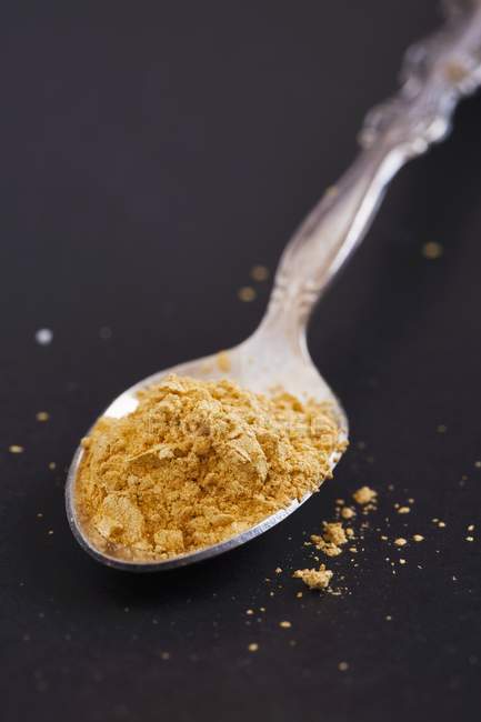 Closeup view of yellow crumbles on silver spoon — Stock Photo