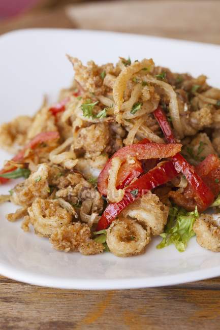 Closeup view of fried calamari with red bell pepper and herbs — Stock Photo