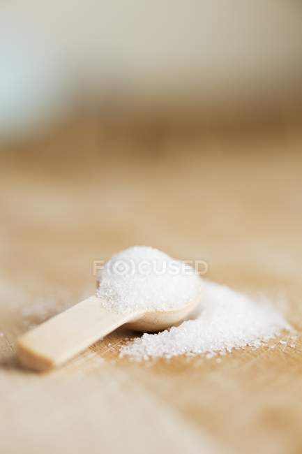 Açúcar granulado em colher de madeira — Fotografia de Stock