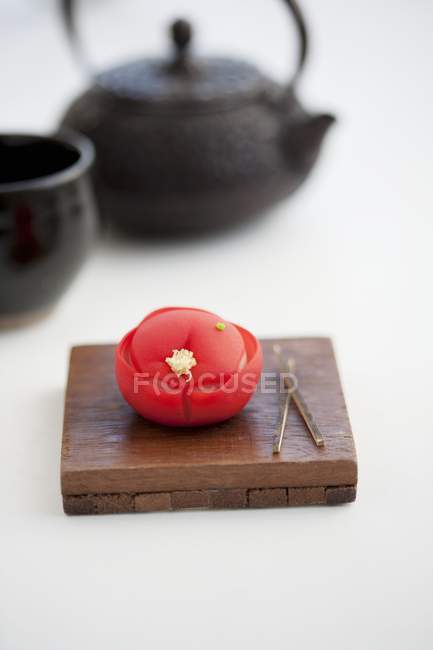 Vista de primer plano de Wagashi camellia sobre tabla de madera con tetera - foto de stock