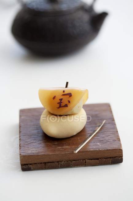 Vista de primer plano de Wagashi con el símbolo japonés para el tesoro, la suerte y el dinero en el tablero de madera - foto de stock