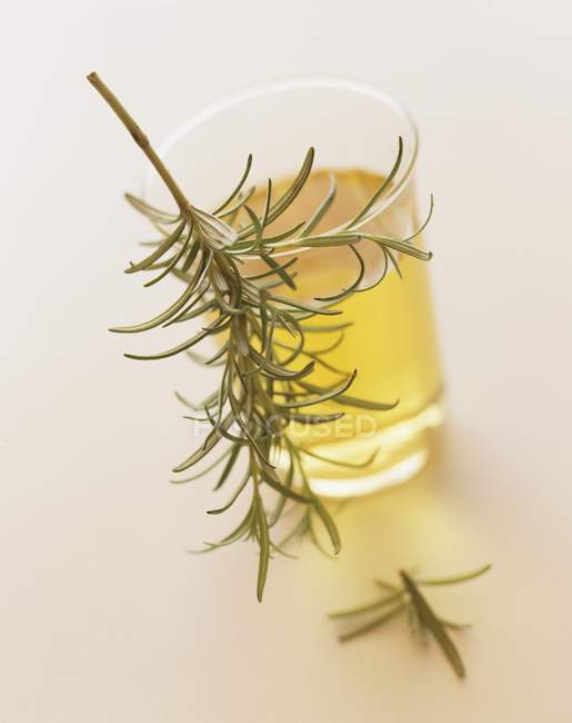 Closeup view of a glass of oil with a sprig of rosemary — Stock Photo
