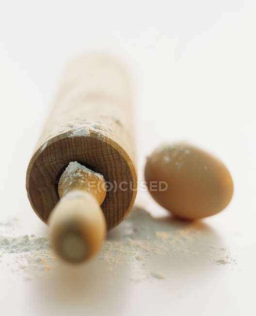 Vista close-up de um rolo de pino, farinha e um ovo — Fotografia de Stock