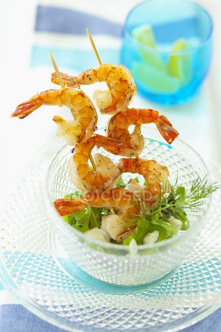 Deep-fried prawn skewers with rocket and fennel in glass bowl over plate — Stock Photo