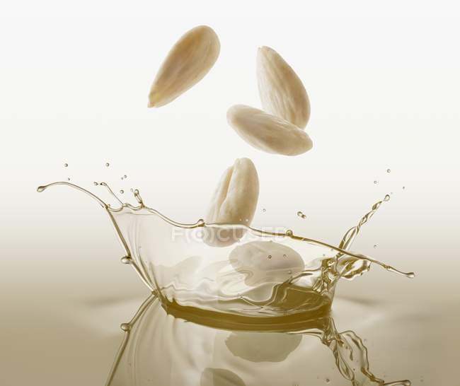 Almonds falling into oil — Stock Photo