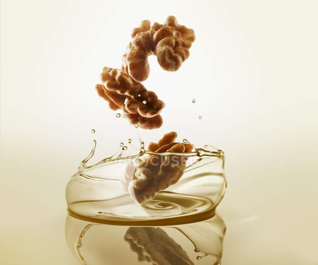 Walnuts falling into oil — Stock Photo