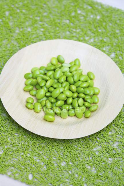 Shelled Edamame  on white plate over green surface — Stock Photo