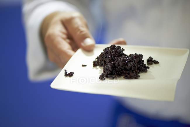 Homem segurando prato com arroz preto — Fotografia de Stock