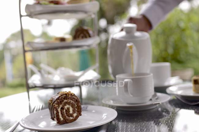 Vista diurna de té y pasteles en la mesa al aire libre - foto de stock