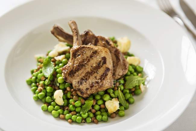 Grilled lamb chops on peas — Stock Photo