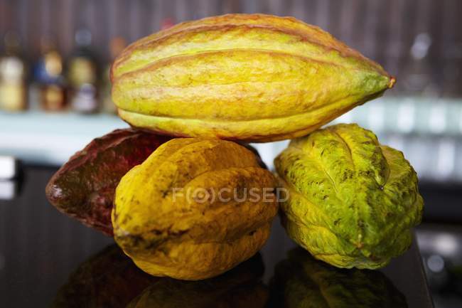 Крупный план четырех стручков какао на отражающей темной поверхности — стоковое фото
