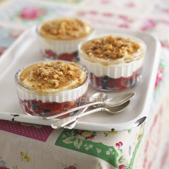 Closeup view of cream with crumbles and berries in glass bowls — Stock Photo
