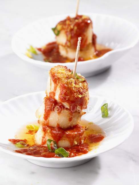 Une brochette de pétoncles avec sauce tomate sur assiettes blanches — Photo de stock