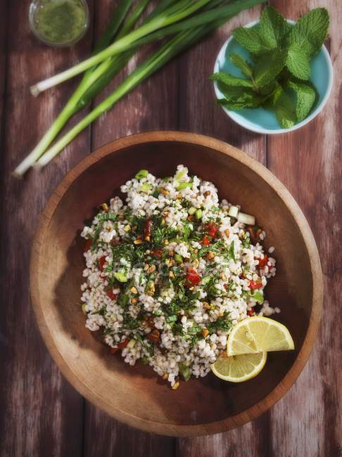 Closeup view of Tabbouleh salad with fresh mint, lemon slices and leek — Stock Photo