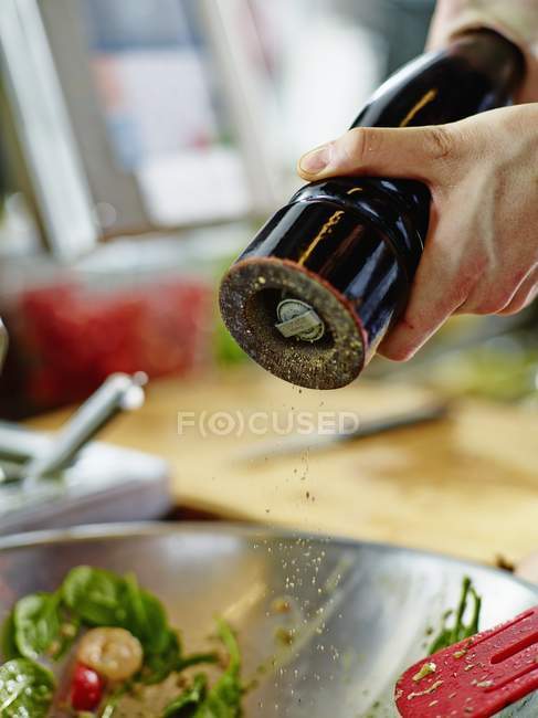 Person peppering salad with mill — Stock Photo