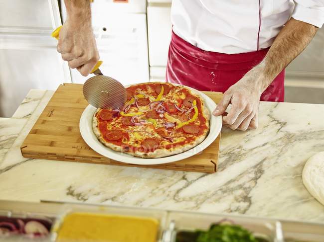Chef cortando pizza - foto de stock