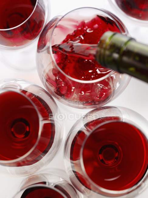 Vinho tinto sendo derramado em copos — Fotografia de Stock