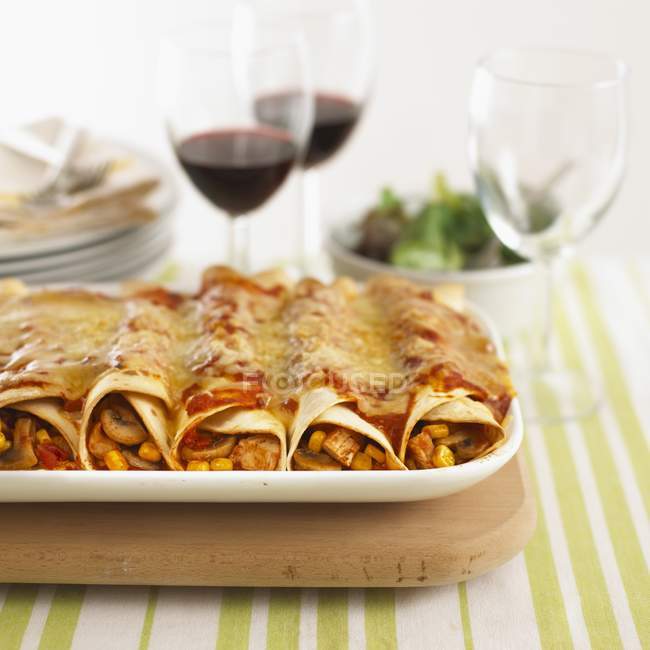 Filled tortilla rolls topped with cheese — Stock Photo