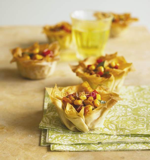 Filo pastry baskets filled with vegetable chilli over wooden surface with towel — Stock Photo